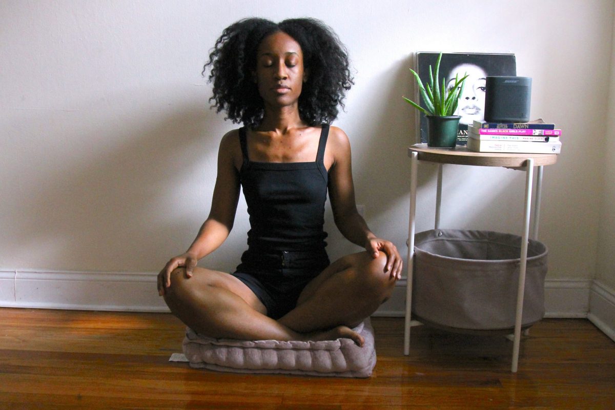 Woman sitting on a yoga cushion in a seated position with her hands on her knees.